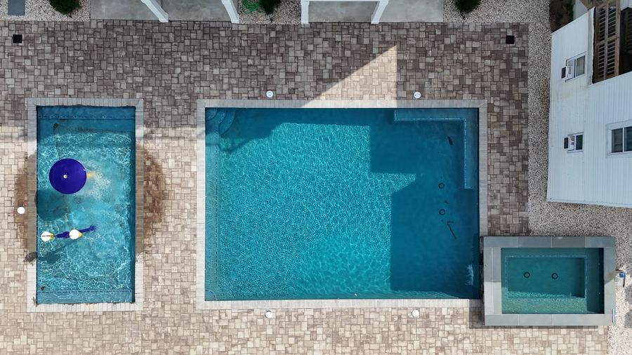 Overhead view of the Kays Oasis pool, plunge pool, and spa set in a stone paver deck