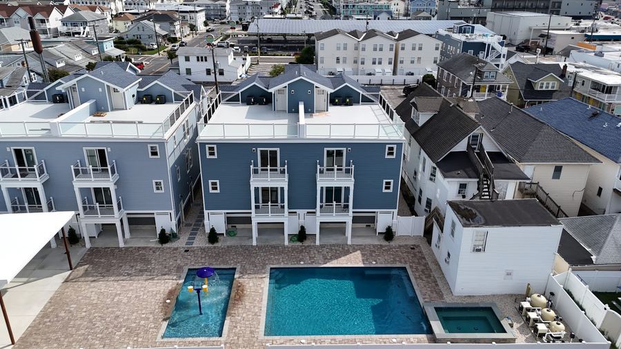 Back of the two blue Kays Oasis homes with the pool deck in front of them