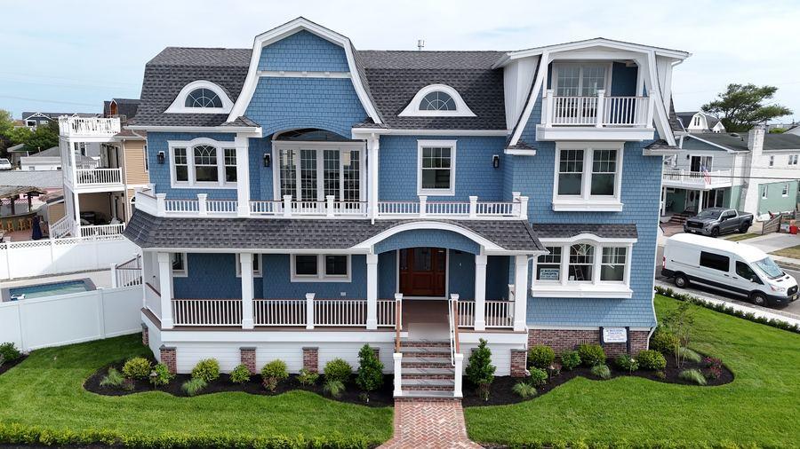 Front of a blue gambrel-roof home in Wildwood Crest with a wraparound porch and new landscaping