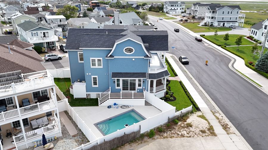 Side of the Wildwood Crest home with the backyard pool, patio, and white privacy fence