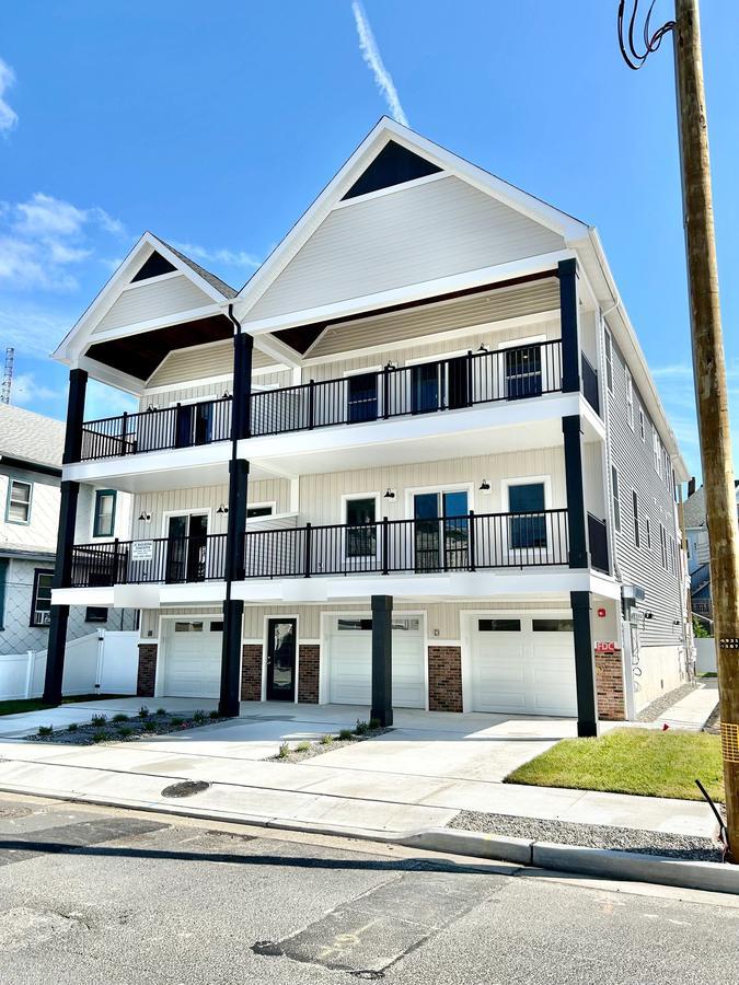 Three-story home with white siding and black balcony railings