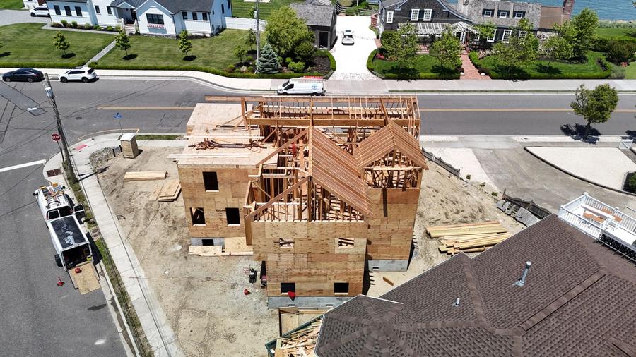 Framed new home on a corner lot with lumber staged around it