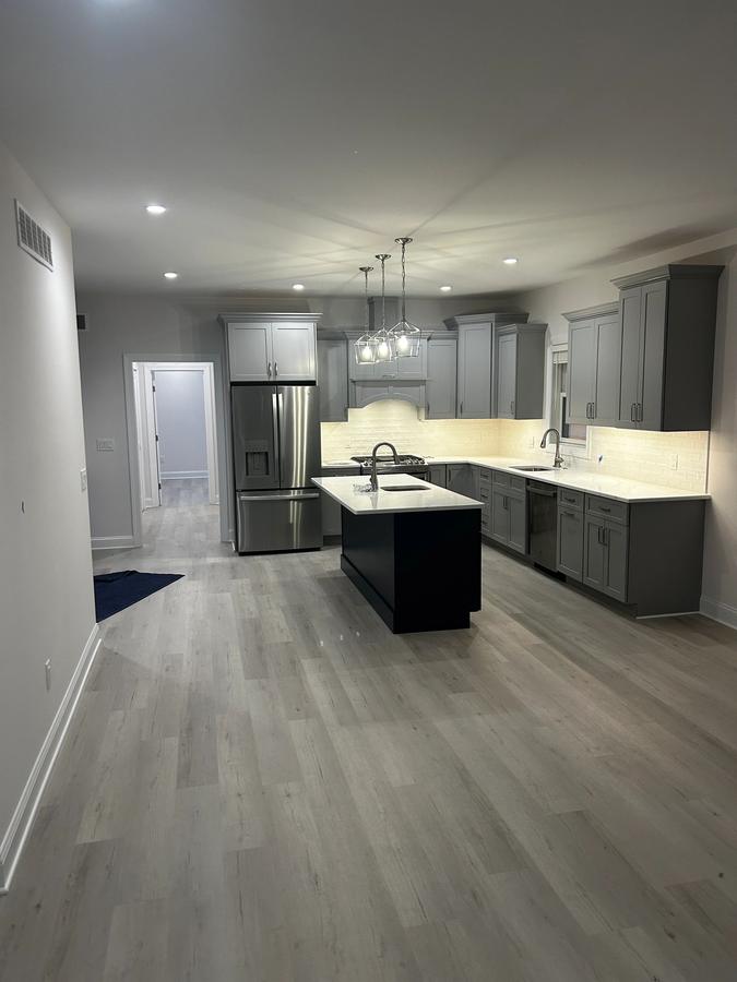 Kitchen with gray cabinets, a black island, and stainless steel appliances