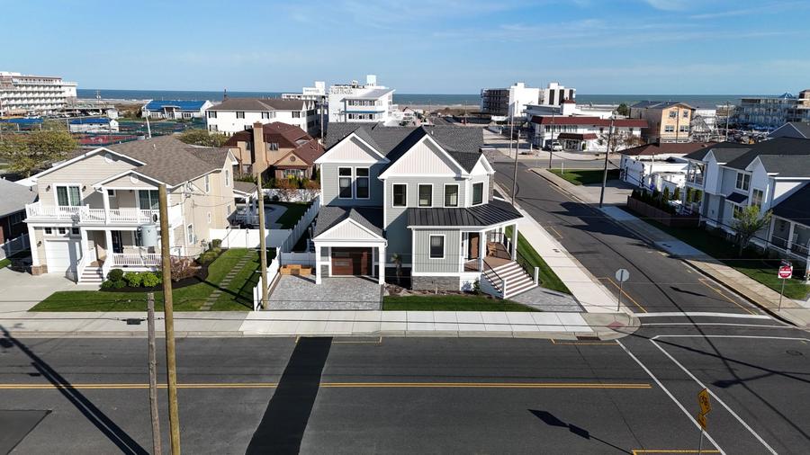 Aerial view of a pair of new two-story homes on a corner lot near the beach